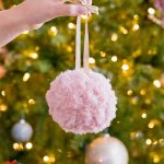 Christmas Crochet Fluffy Ornament. One pink pompom in front of the tree || thecrochetspace.com