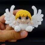 Christmas Crochet Key-Ring Angel. Crafted in sitting position, with black backdrop, short yellow hair with a fringe and large white wings || thecrochetspace.com