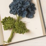 Classic Crochet Hydrangea Branch laying across an open page in a book. Blue flowers and 2 leaves || thecrochetspace.com