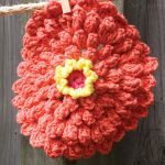 Crochet Zinnia Dishcloth. Orange flower on a washing line || thecrochetspace.com