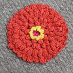 Crochet Zinnia Dishcloth. Orange flower with yellow accent center || thecrochetspace.com