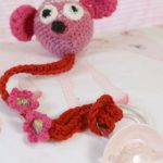 Crocheted Baby Pacifier Holder. Crafted in pink. Amigurumi head with long tail to attached pacifier || thecrochetspace.com