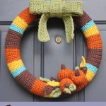 Delightful Crocheted Fall Wreath. The complete wreath on a door. With bow and pumpkin accents || thecrochetspace.com