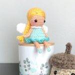 Fairie Pixie Crochet Doll, sitting on a pot. She is not wearing a hat just her dress in blue and her wings || thecrochetspace.com