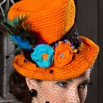 Halloween Crochet Top Hat. Orange hat styled with blue feather and orange and blue crocheted flowers | thecrochetspace.com