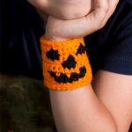 Halloween Pumpkin Crochet Cuff . Orange cuff with black pumpkin face| thecrochetspace.com