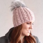 Heavy Crochet Cable Hat, Side view of hat being worn. Crafted in pink with grey pompom || thecrochetspace.com