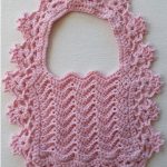 Lacy Crochet Baby Bib In Baby Pink And Surrounded By A Beautiful Wide Lace Border || thecrochetspace.com