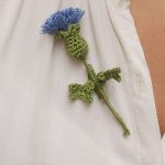 Scottish Thistle Crochet Flora. Depicted as a brooch. Blue flower head and two leaves || thecrochetspace.com