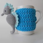 Seahorse Crocheted Mug Cozy. Mug cozy crafted in blue with grey seahorse on the side || thecrochetspace.com