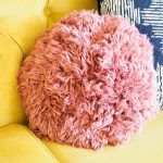 Super Shaggy Crochet Pillow. Sitting on a yellow sofa || thecrochetspace.com