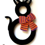 Superstitious Black Cat Crocheted Wreath. Wreath in shape of cat with orange colored scarf bow to the side || thecrochetspace.com